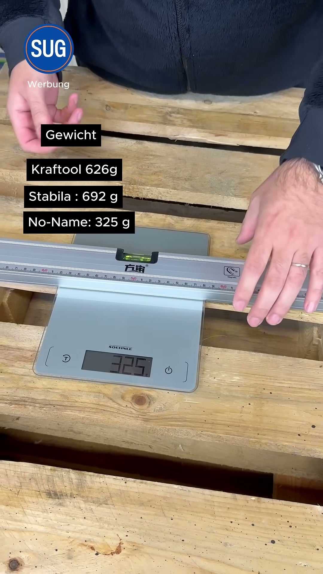 Die graue No-Name-Wasserwaage liegt auf einer digitalen Küchenwaage mit der Anzeige 325 g; eingeblendete Gewichtsliste: Kraftool 626 g, Stabila 692 g, No-Name 325 g.