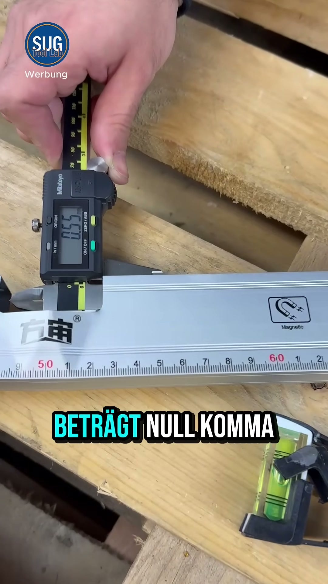 Ein Mitutoyo-Messschieber misst die Profilwand der grauen No-Name-Wasserwaage; das Display zeigt 0,55 mm.