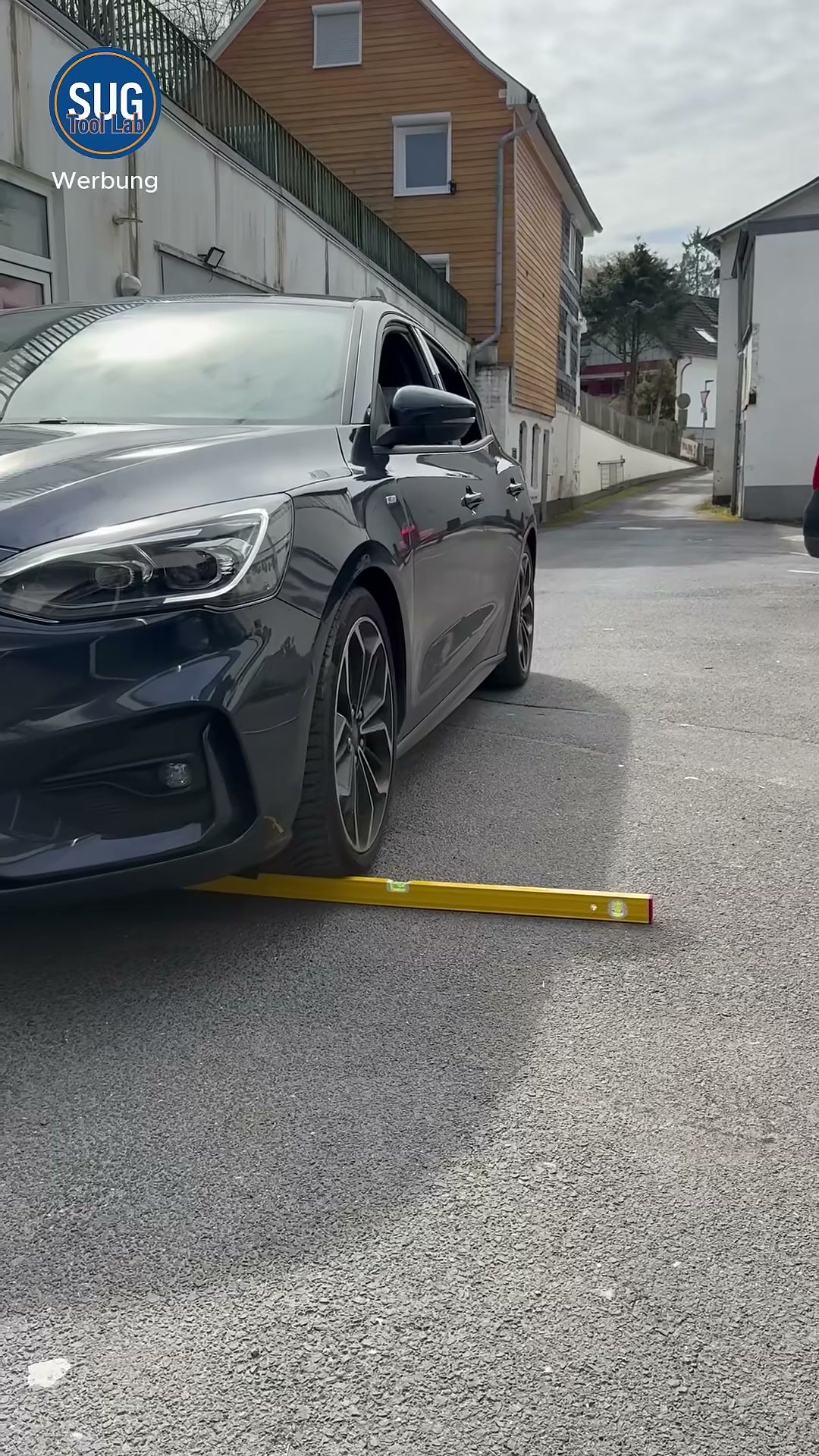 Die gelbe Stabila-Wasserwaage liegt auf einer Straße vor dem Vorderrad eines dunklen Autos, das gleich darüberrollt (Extremtest).
